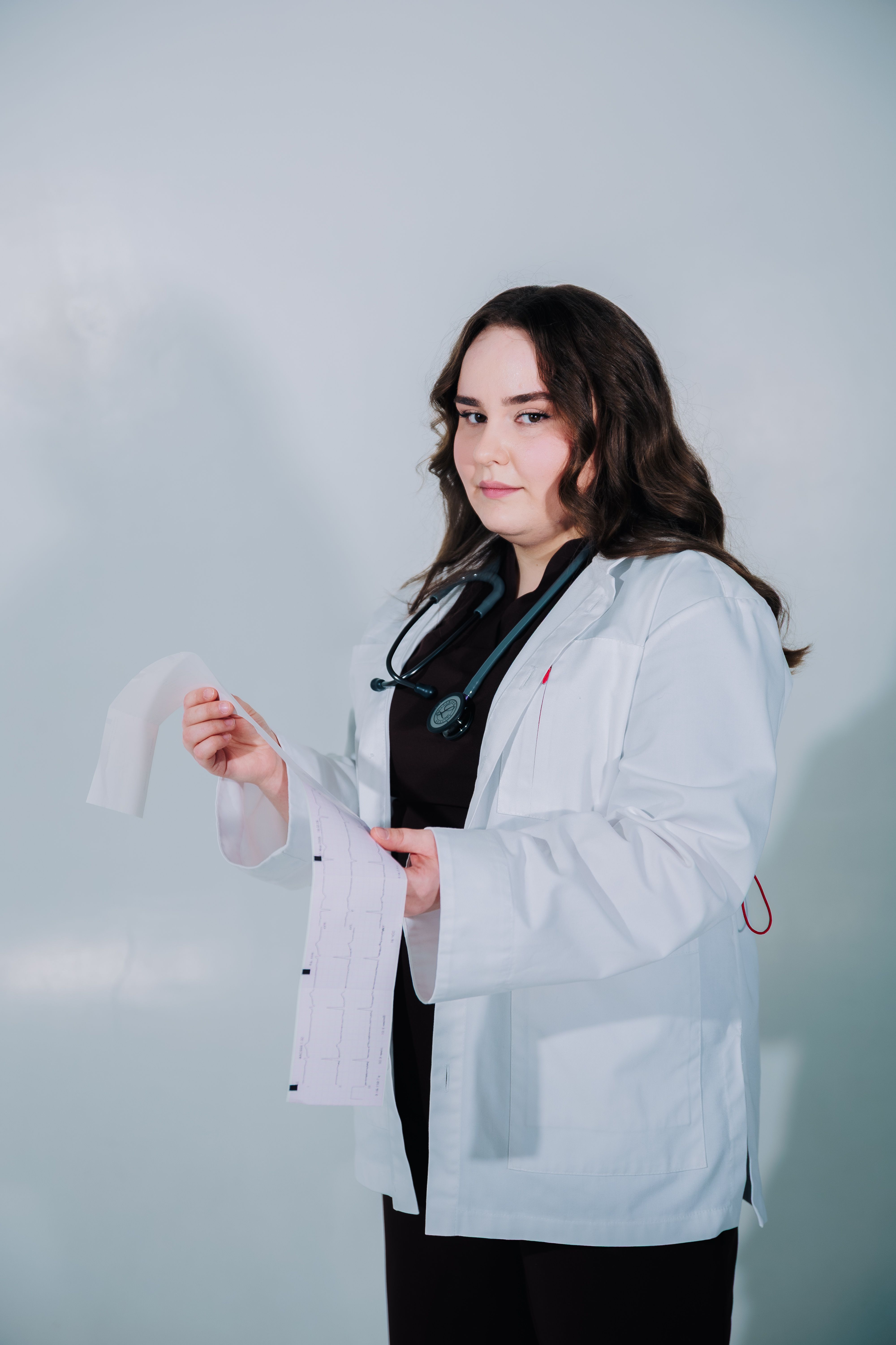 A female doctor in a white coat holding medical documents, showcasing professionalism.