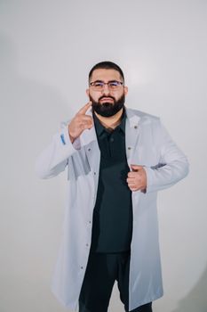 Portrait of a confident male doctor wearing a white coat and glasses against a neutral background.