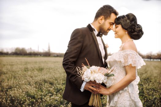 Bride and groom sharing a romantic moment in a scenic outdoor setting with a bouquet.