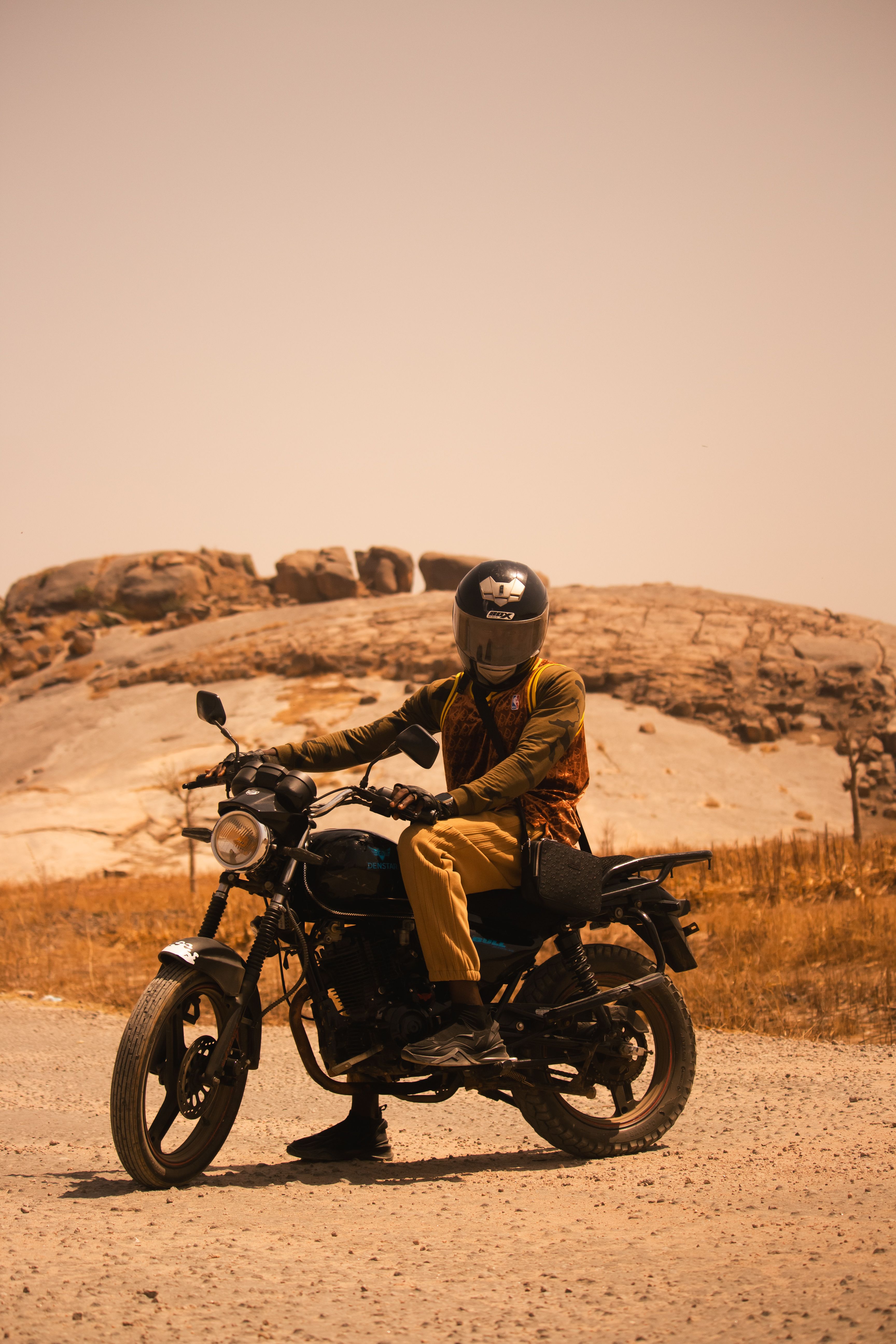 Motorcyclist on Desert Road with Rocky Background · Free Stock Photo