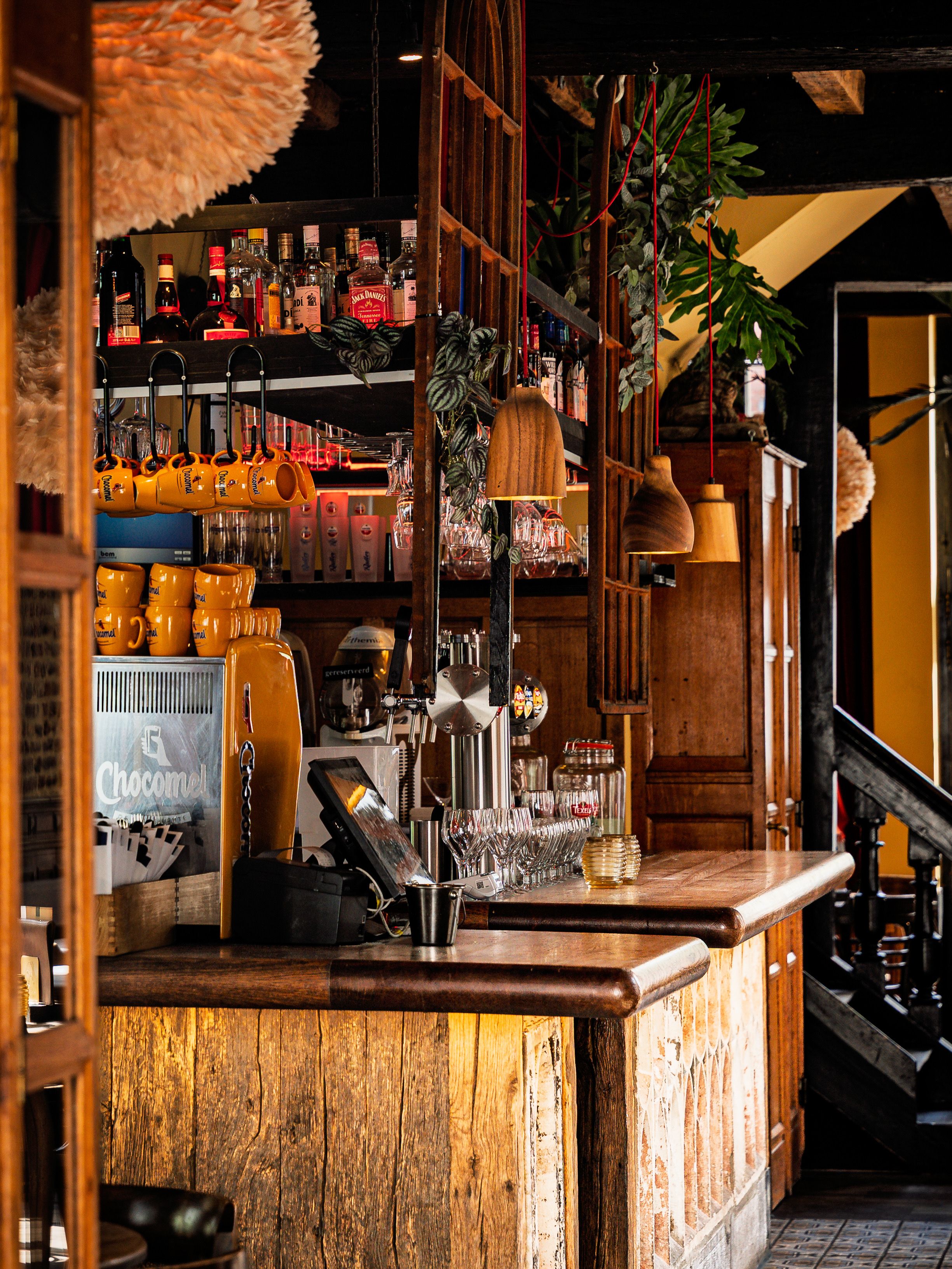 Rustic bar interior featuring wooden decor, warm lighting, and diverse spirits display.