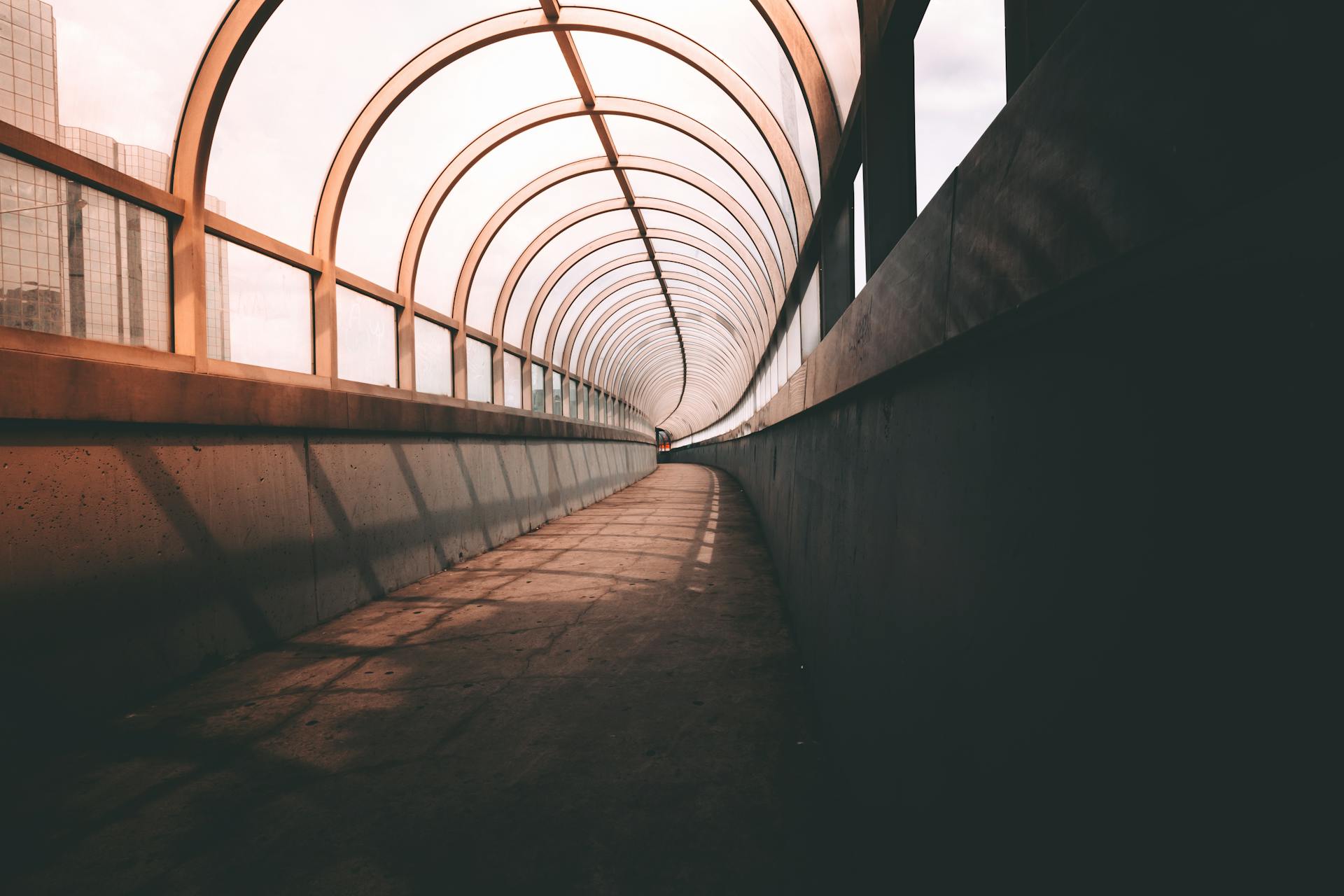 Explore the captivating architecture of a modern glass tunnel with unique lighting and perspective.