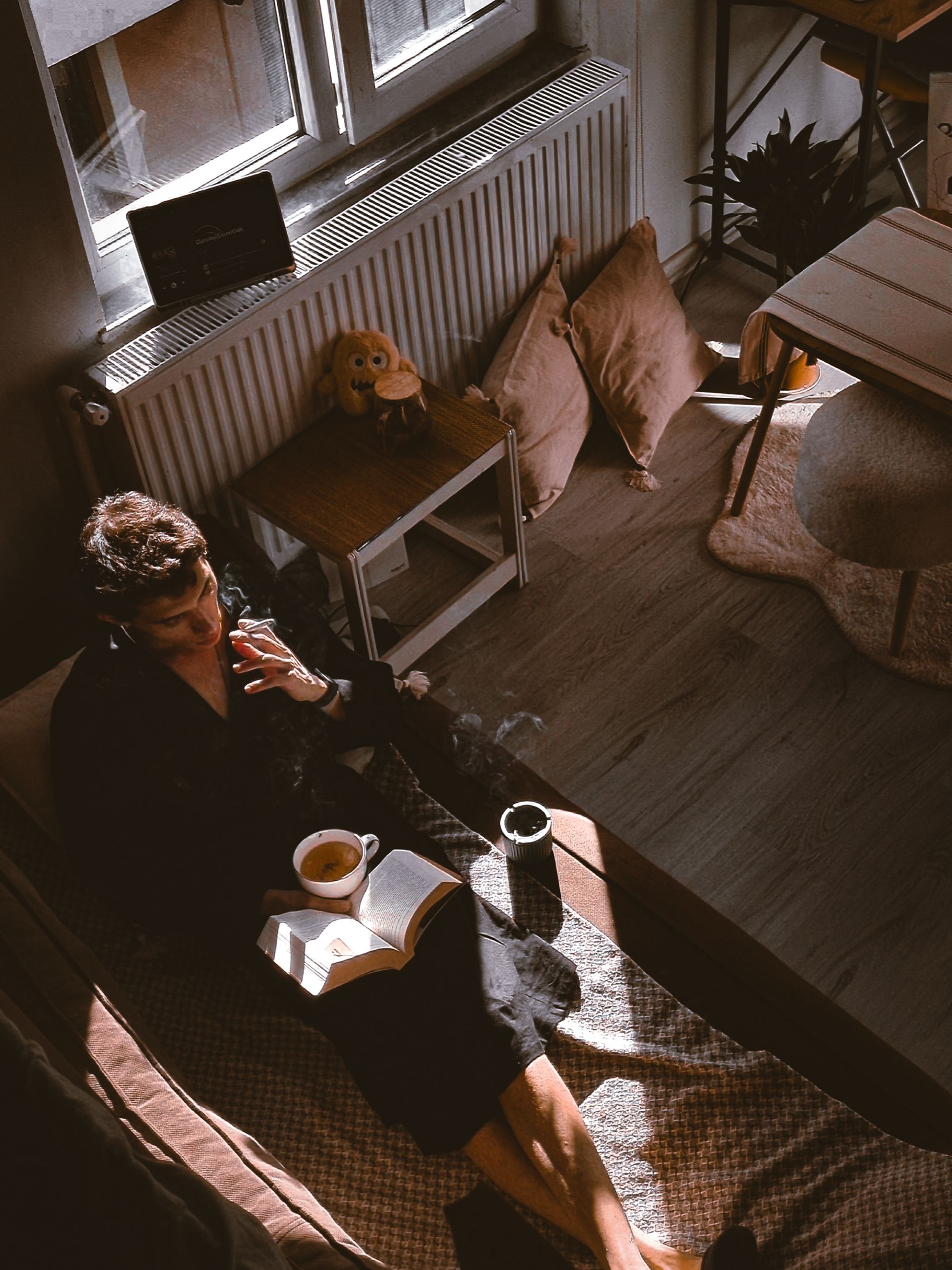 Femme lisant près d’une fenêtre dans un intérieur chaleureux