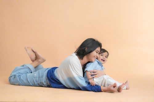 Free Joyful mother and baby bonding on a soft, peach backdrop. Heartwarming embrace and smiles. Stock Photo