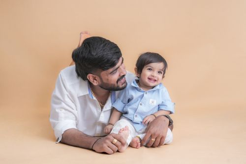 Free Father and baby son smiling while laying on a studio floor. Stock Photo