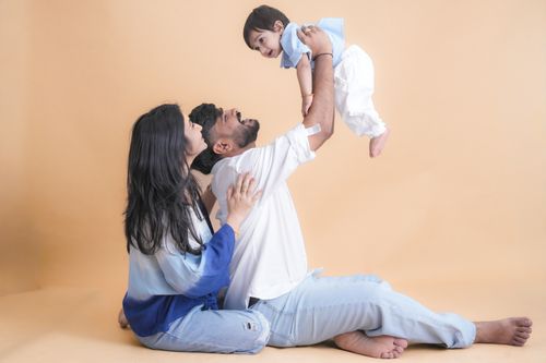 Free A joyful family of three playing together in a bright, minimalist indoor setting. Stock Photo