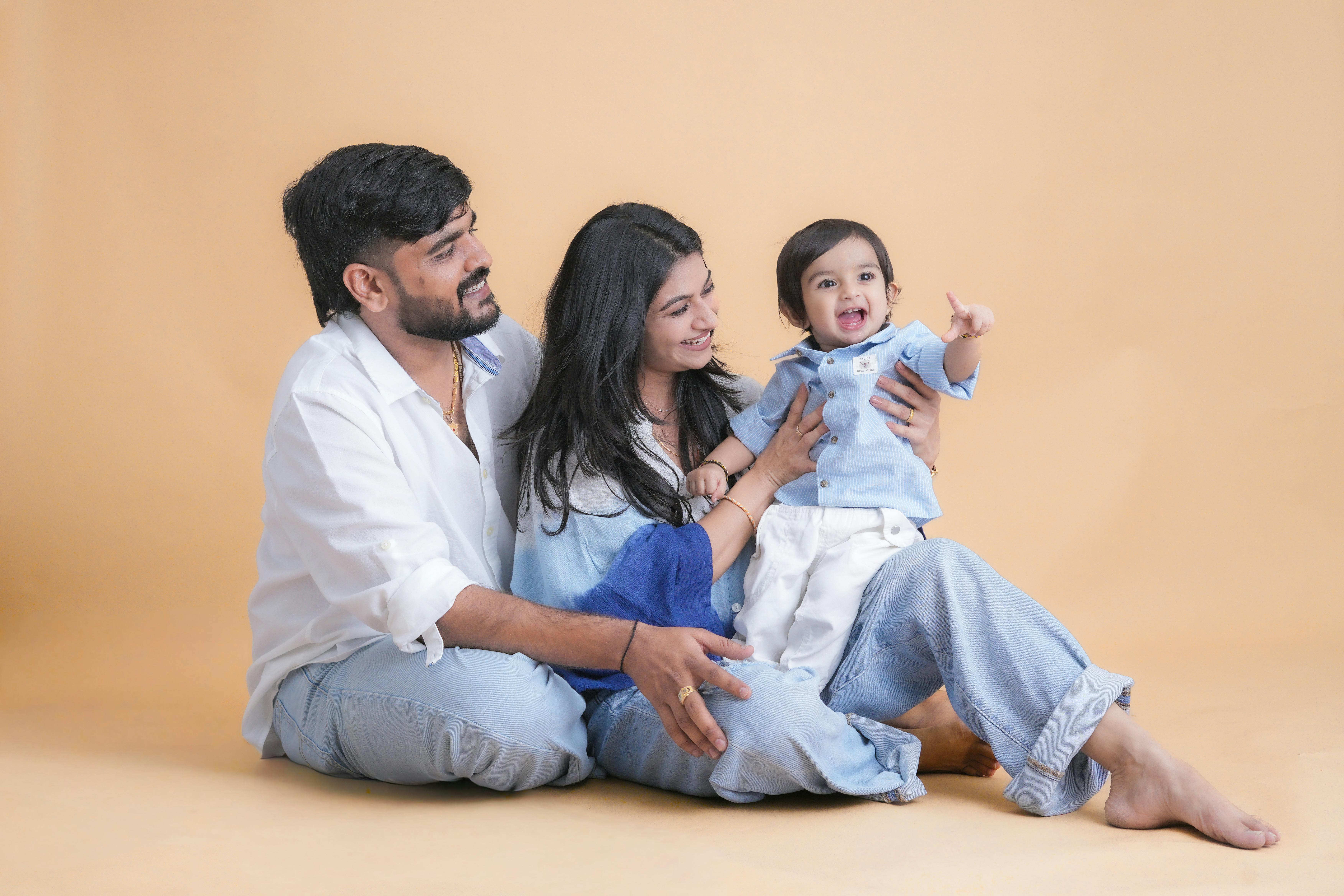 A joyful family portrait featuring parents and their child in a warm studio setting.