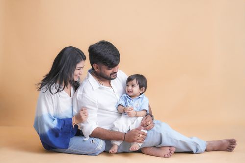 Free A joyful family portrait featuring parents with their smiling baby in a cozy indoor setting. Stock Photo