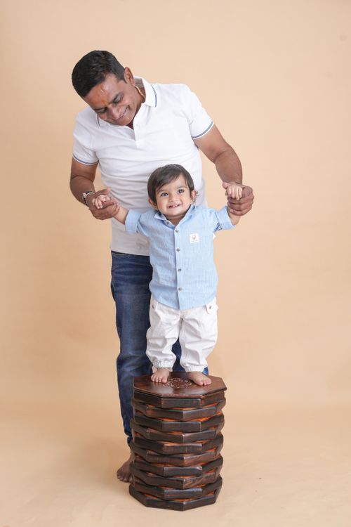 Free Father supports young son standing on stack of wood indoors. Stock Photo