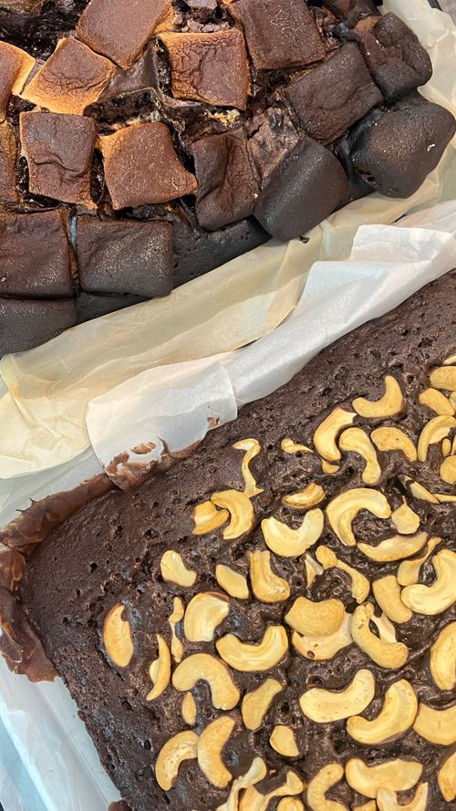 Free Close-up of two types of chocolate brownies with cashew and marshmallow toppings on baking paper. Stock Photo