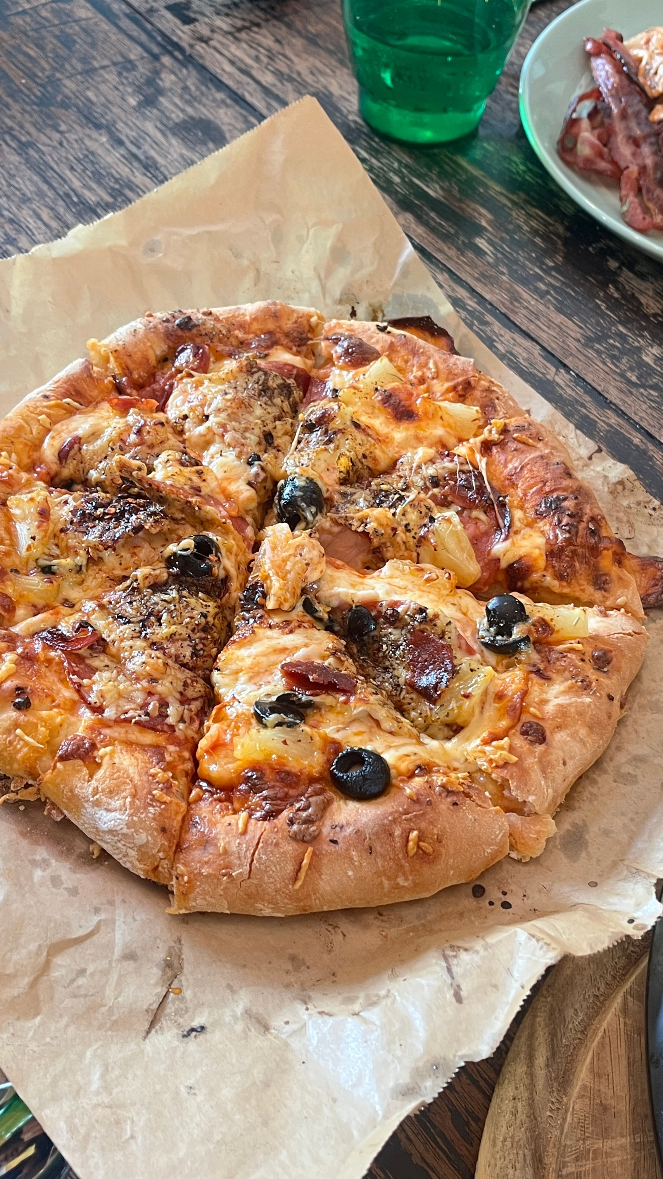 Freshly baked homemade pizza topped with olives and cheese on a wooden table.