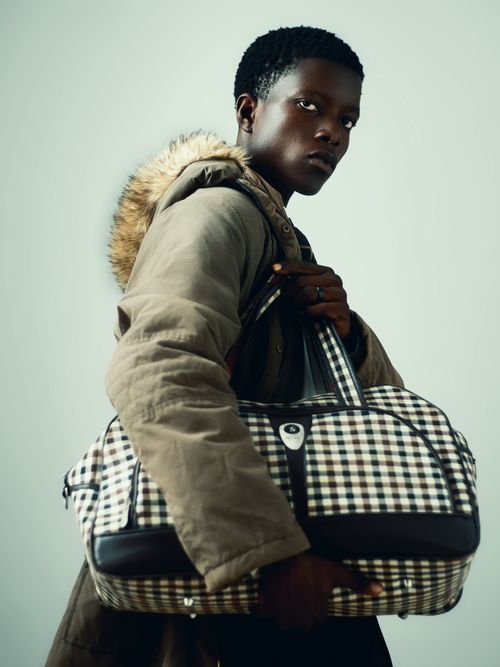 Free Person in winter coat and checkered bag showcasing fashion style. Stock Photo