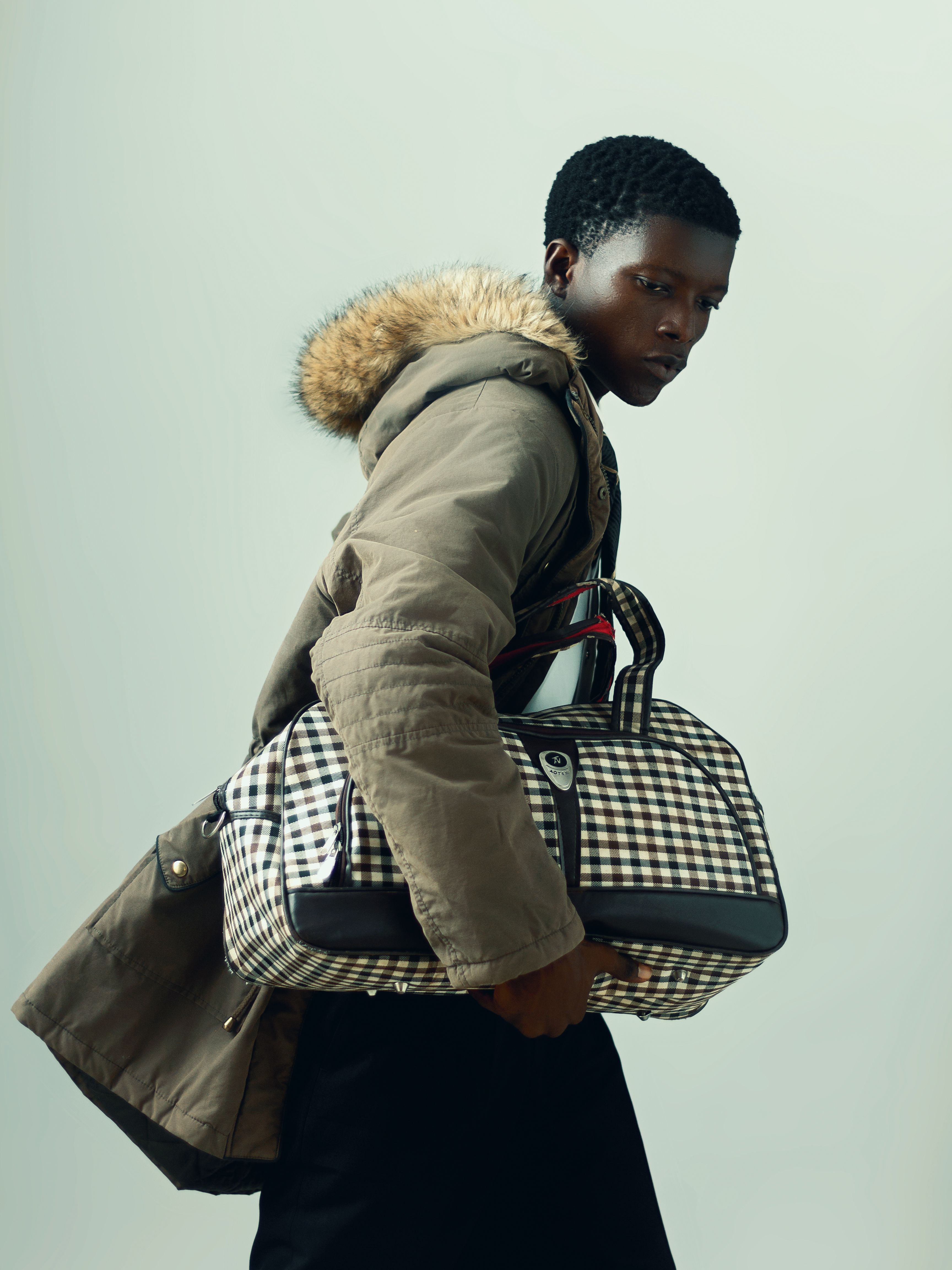 Fashion-forward young adult with a chic winter coat and stylish checkered bag.