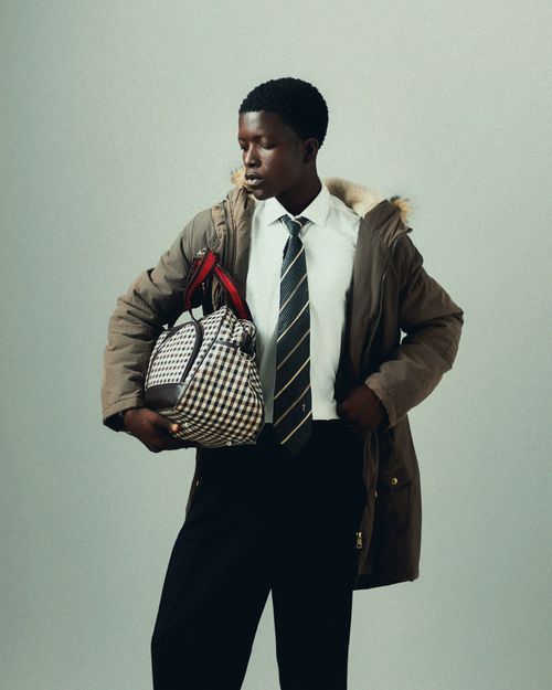 Free Young adult male in formal wear holding a plaid bag confidently. Stock Photo