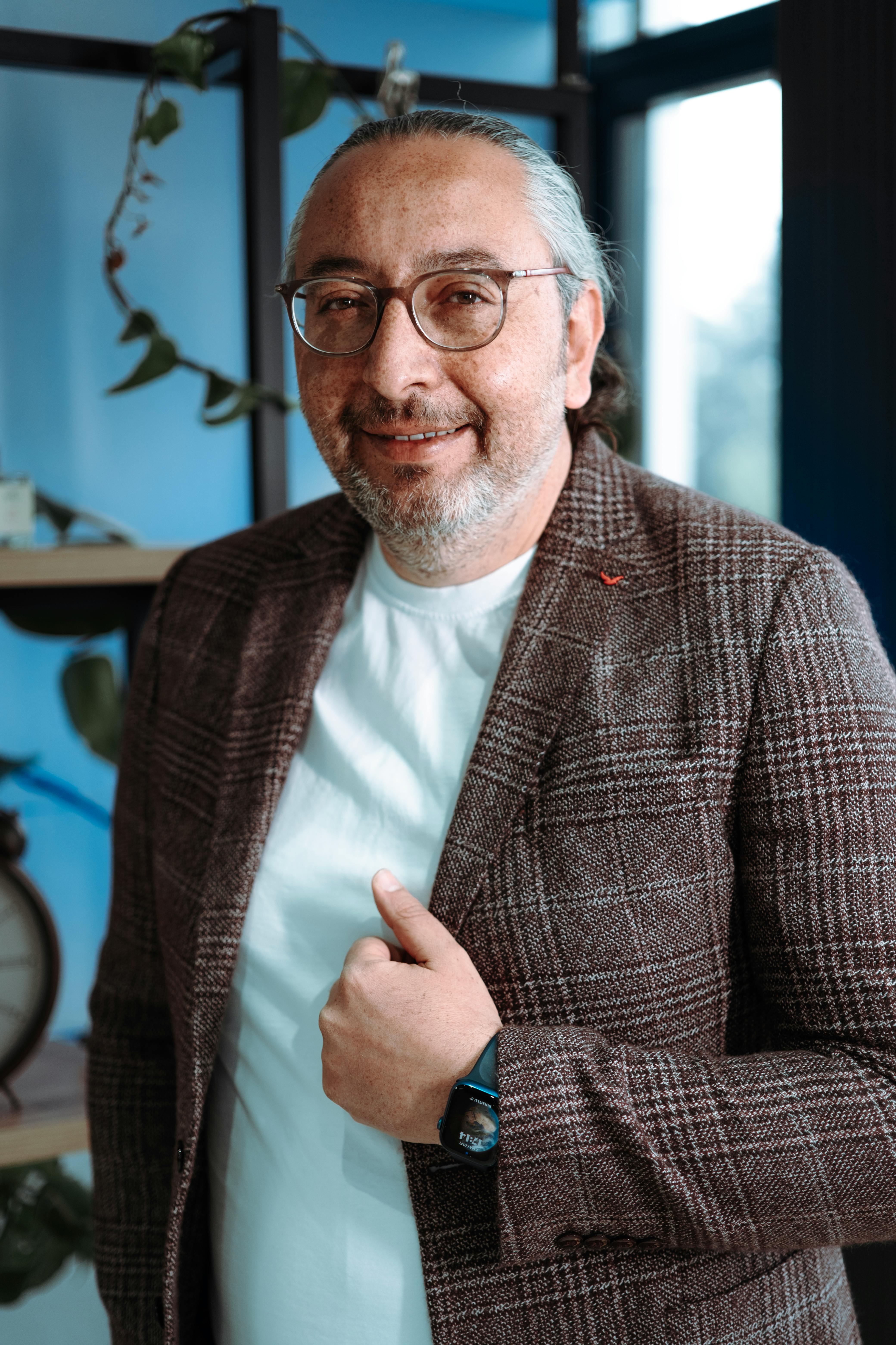 Portrait of a relaxed senior man in casual attire indoors, exuding confidence and warmth.