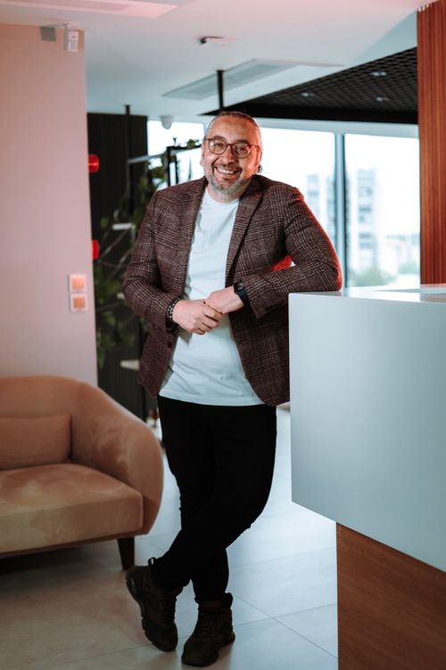 Free Confident middle-aged man in stylish attire standing in a contemporary office environment. Stock Photo
