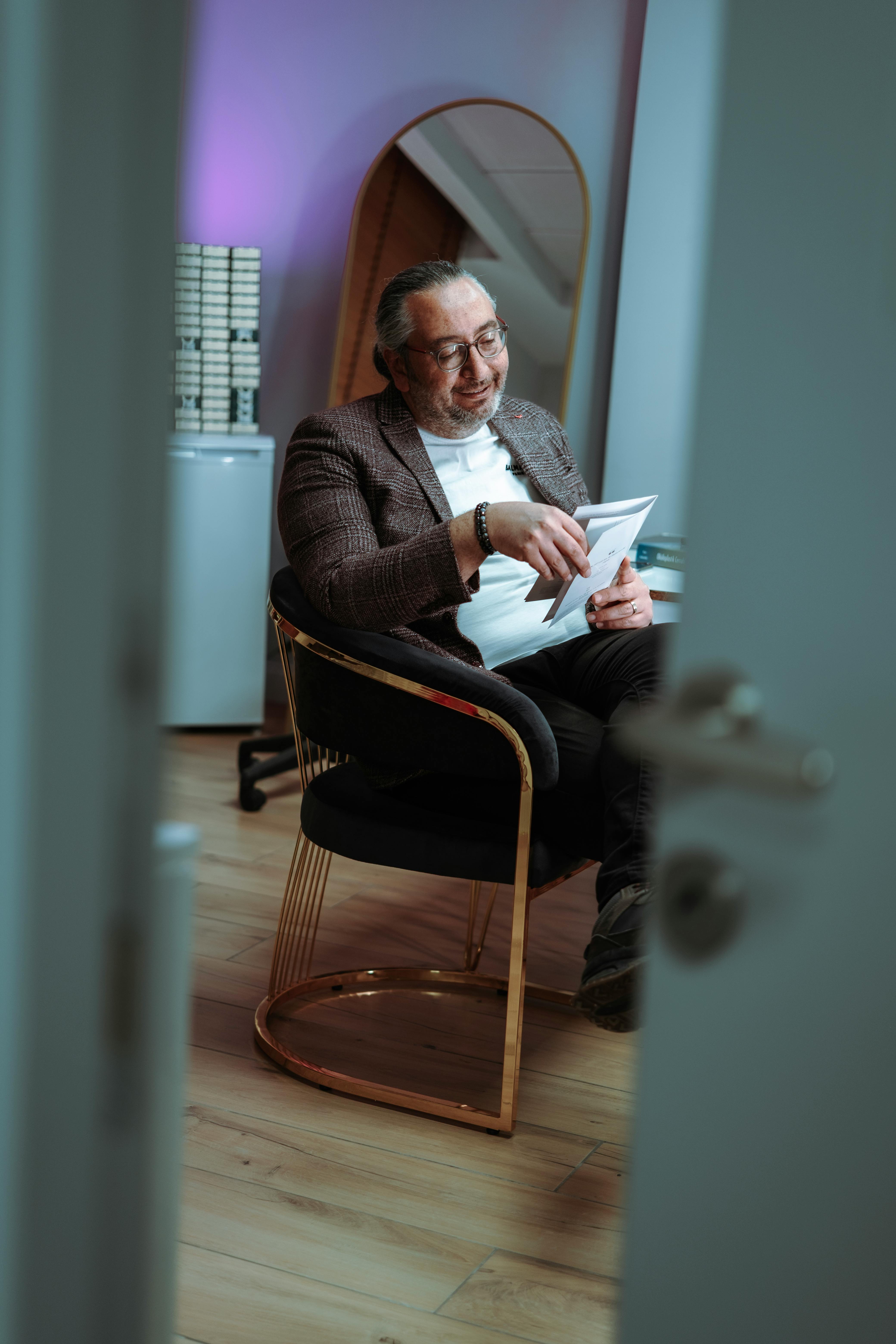 Middle-aged man reading a document in a stylish office setting with ambient lighting.