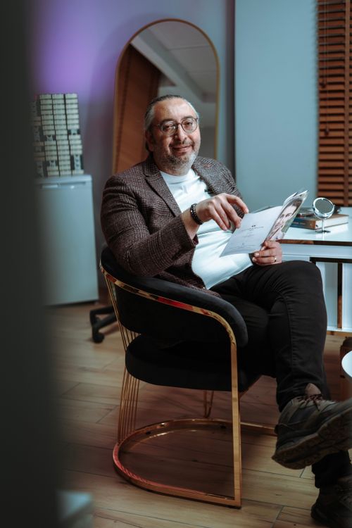Free A man in a modern office environment, sitting casually with a magazine, exuding a relaxed and professional vibe. Stock Photo