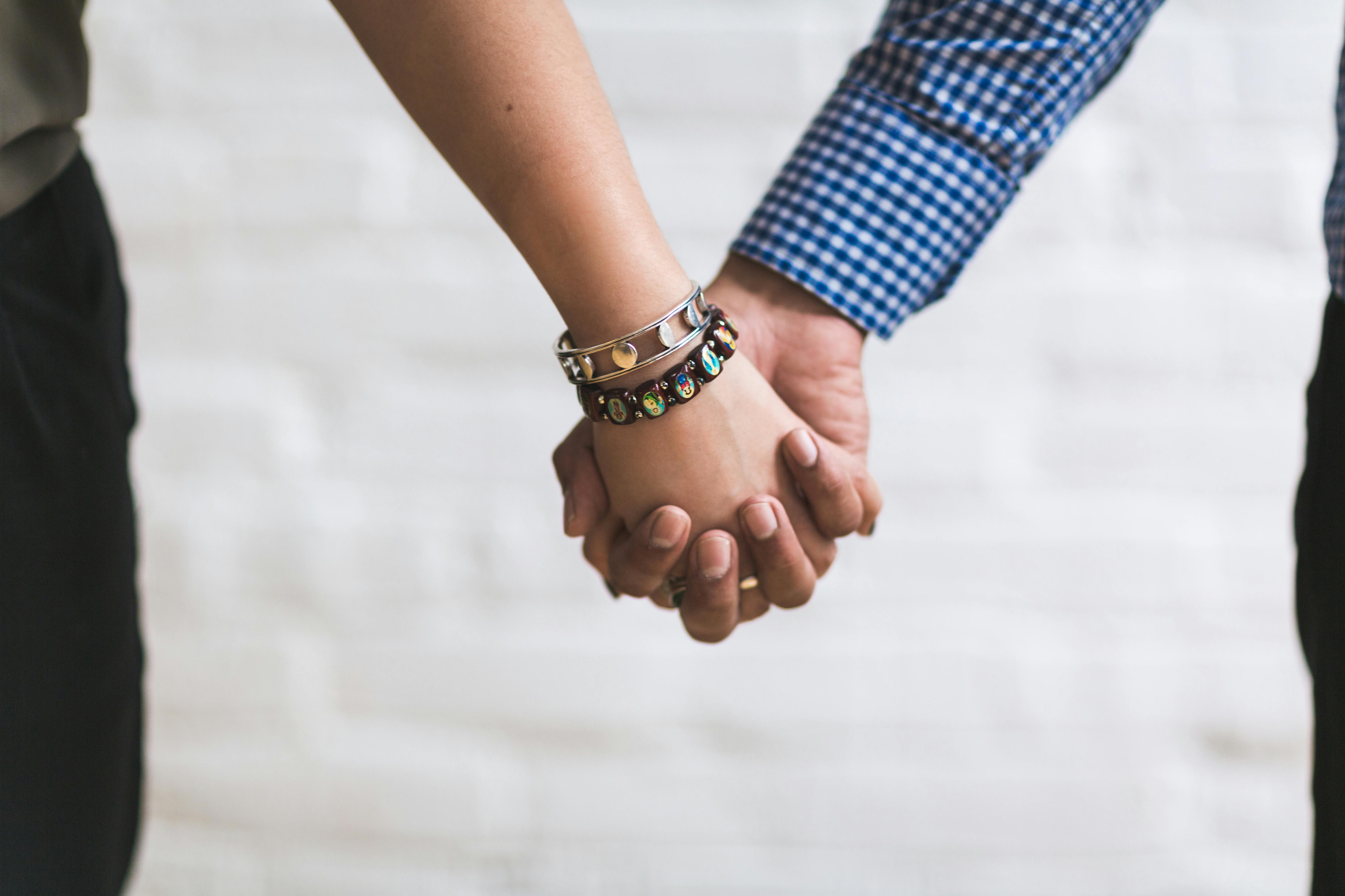 Couple Holding Hands Near White Painted Wall Free Stock Photo