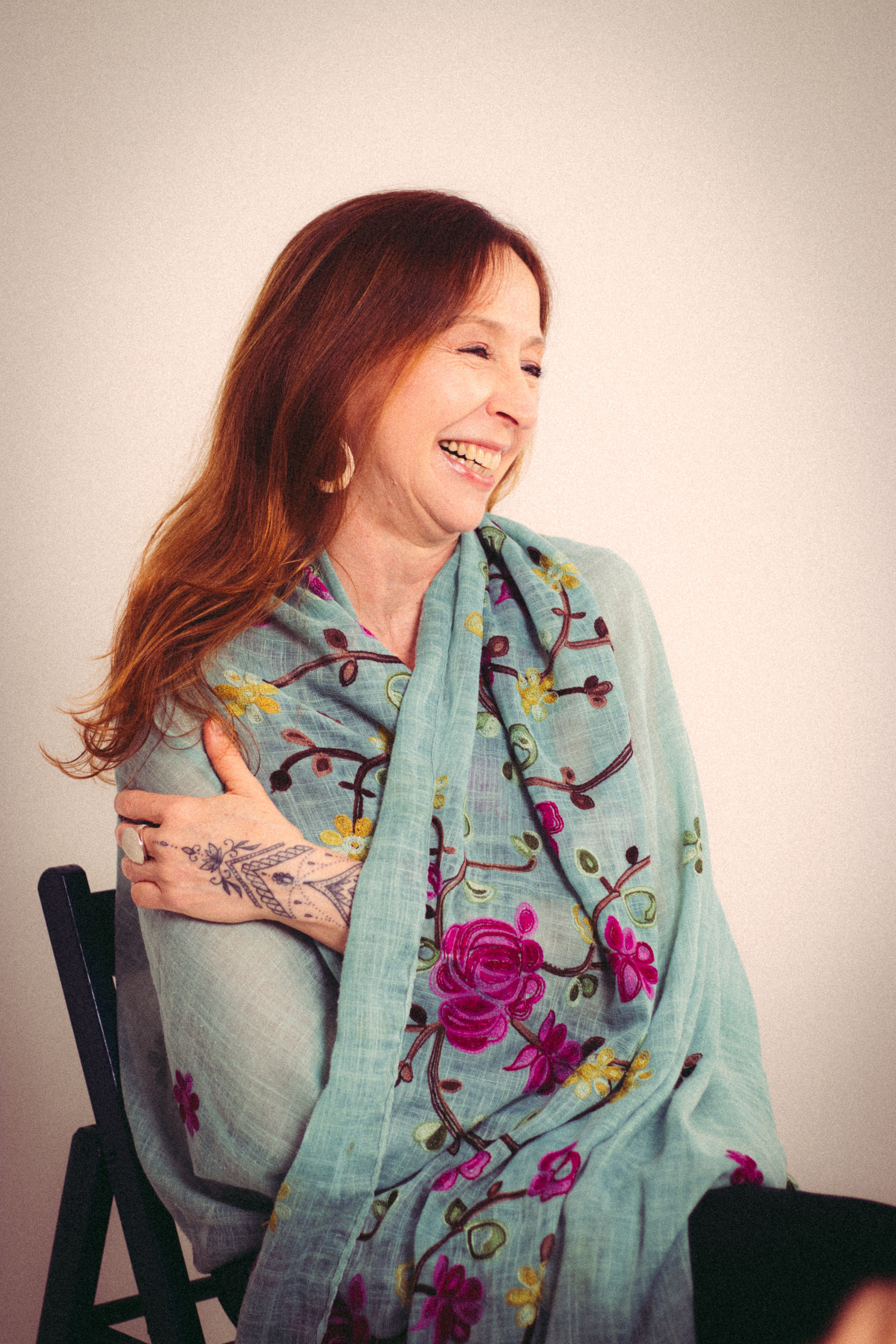 Happy woman with long hair in floral scarf laughing joyfully.