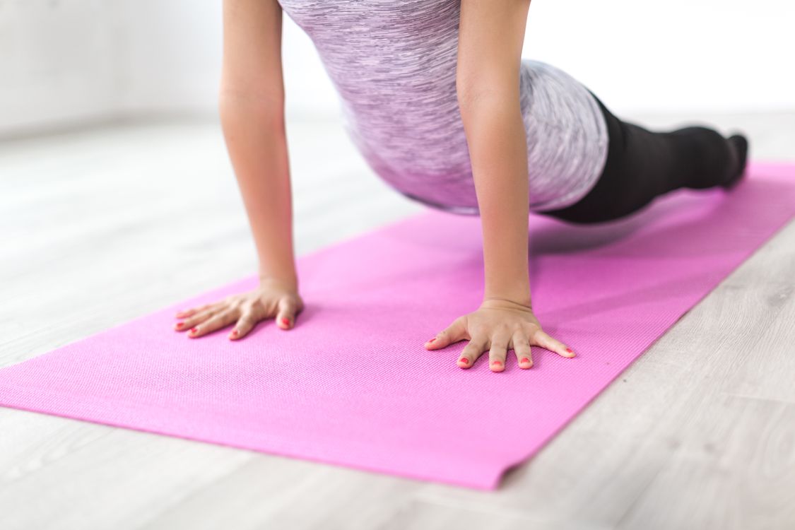 Person performing a Pilates stretch in a bright, tidy living room