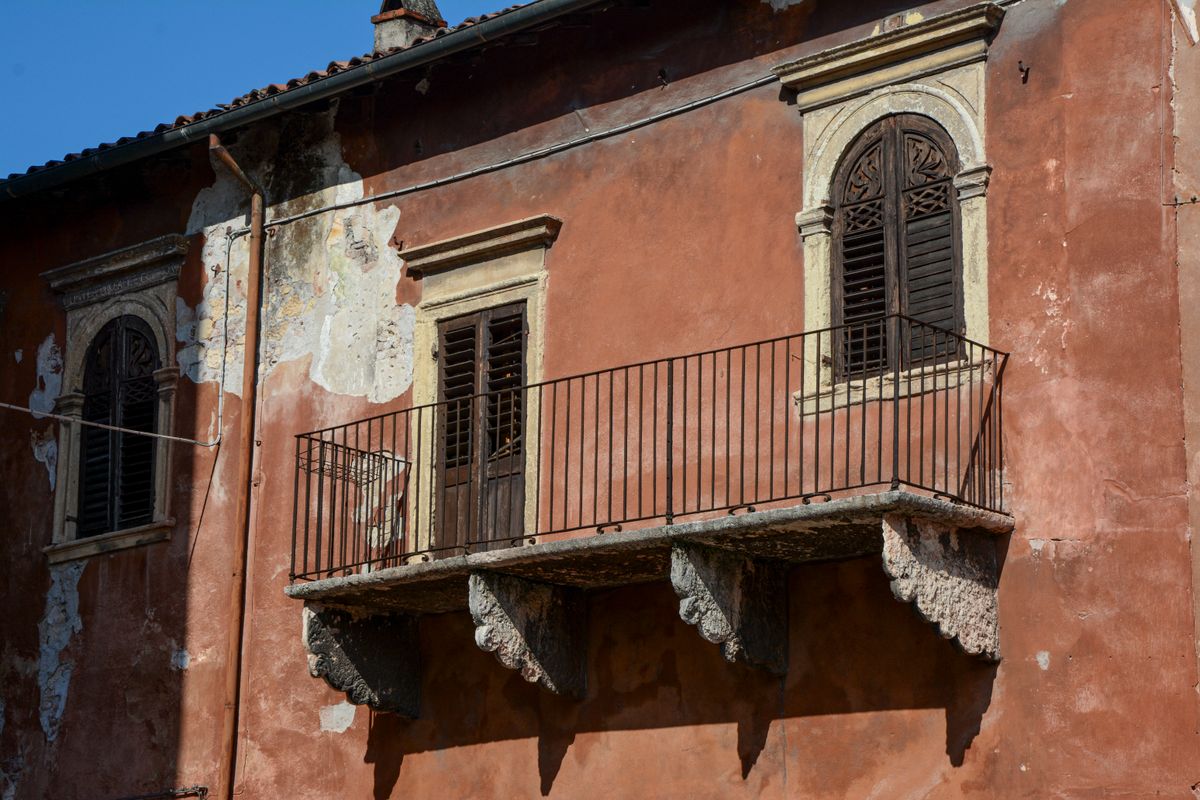 Balcon rustic de piatra pe o fatada de culoarea terracotei