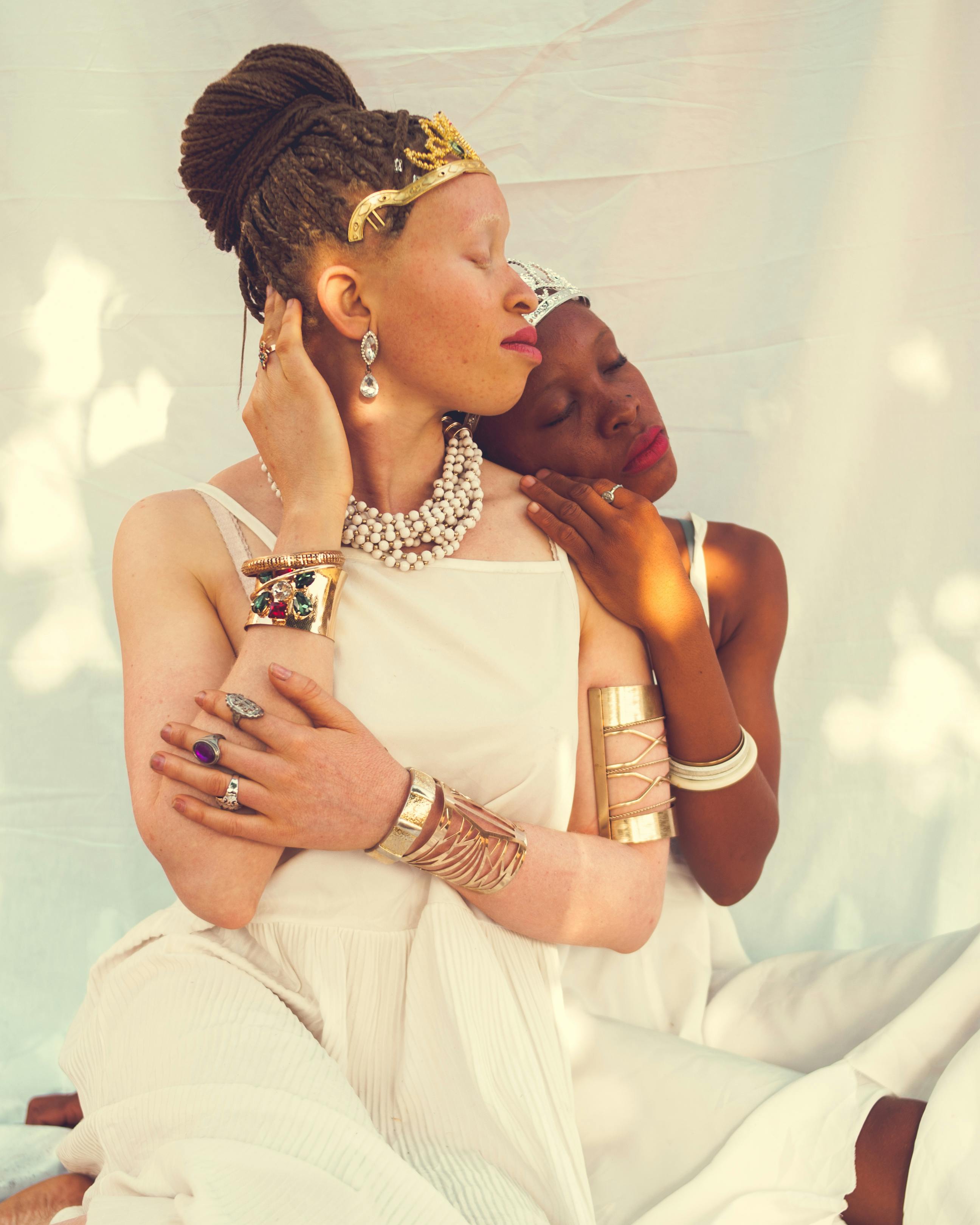 Serene portrait of two women with jewelry and braided hairstyles. A moment of connection and support.