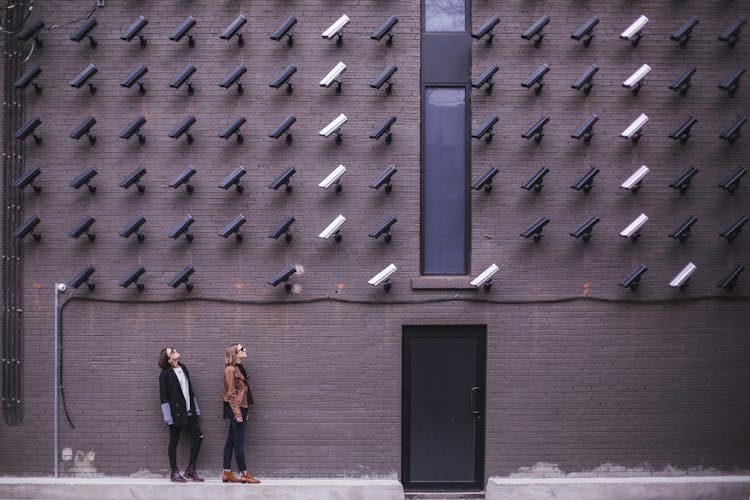 Two Person Standing Under Lot Of Bullet Cctv Camera