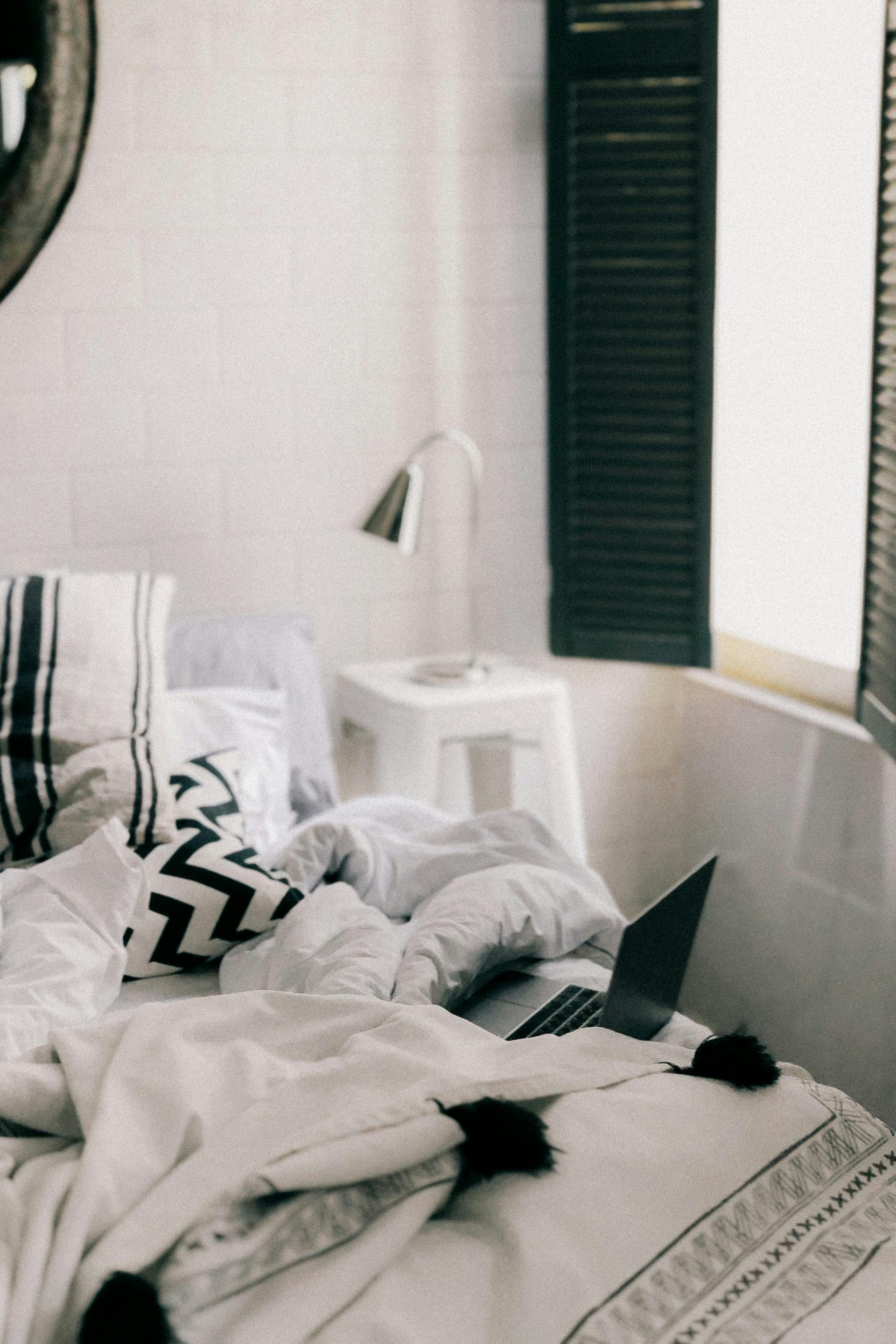 Unmade bed with laptop in stylish bedroom \u00b7 Free Stock Photo