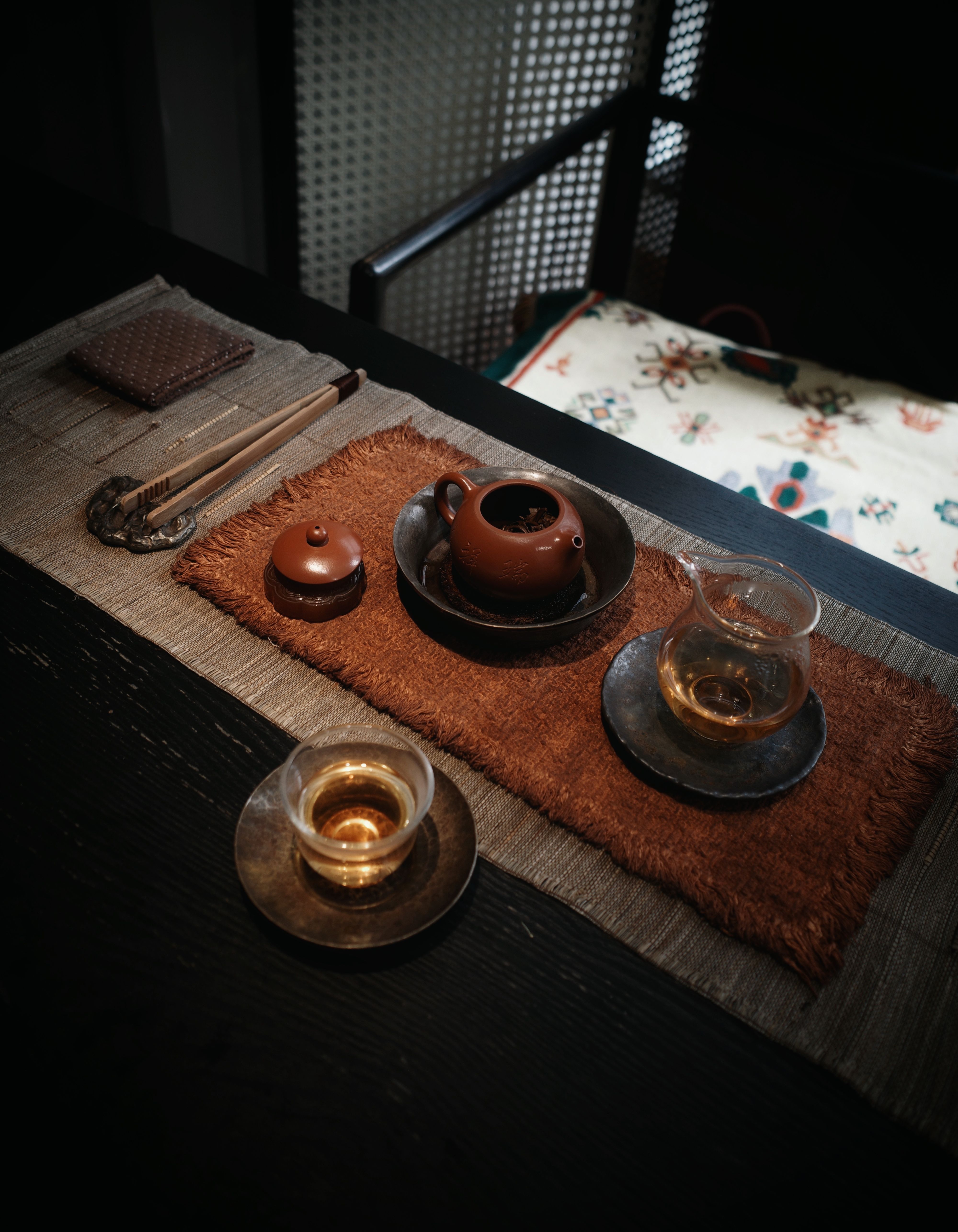 Elegant traditional Chinese tea ceremony setup with clay teapot and glass cups on a rustic mat.