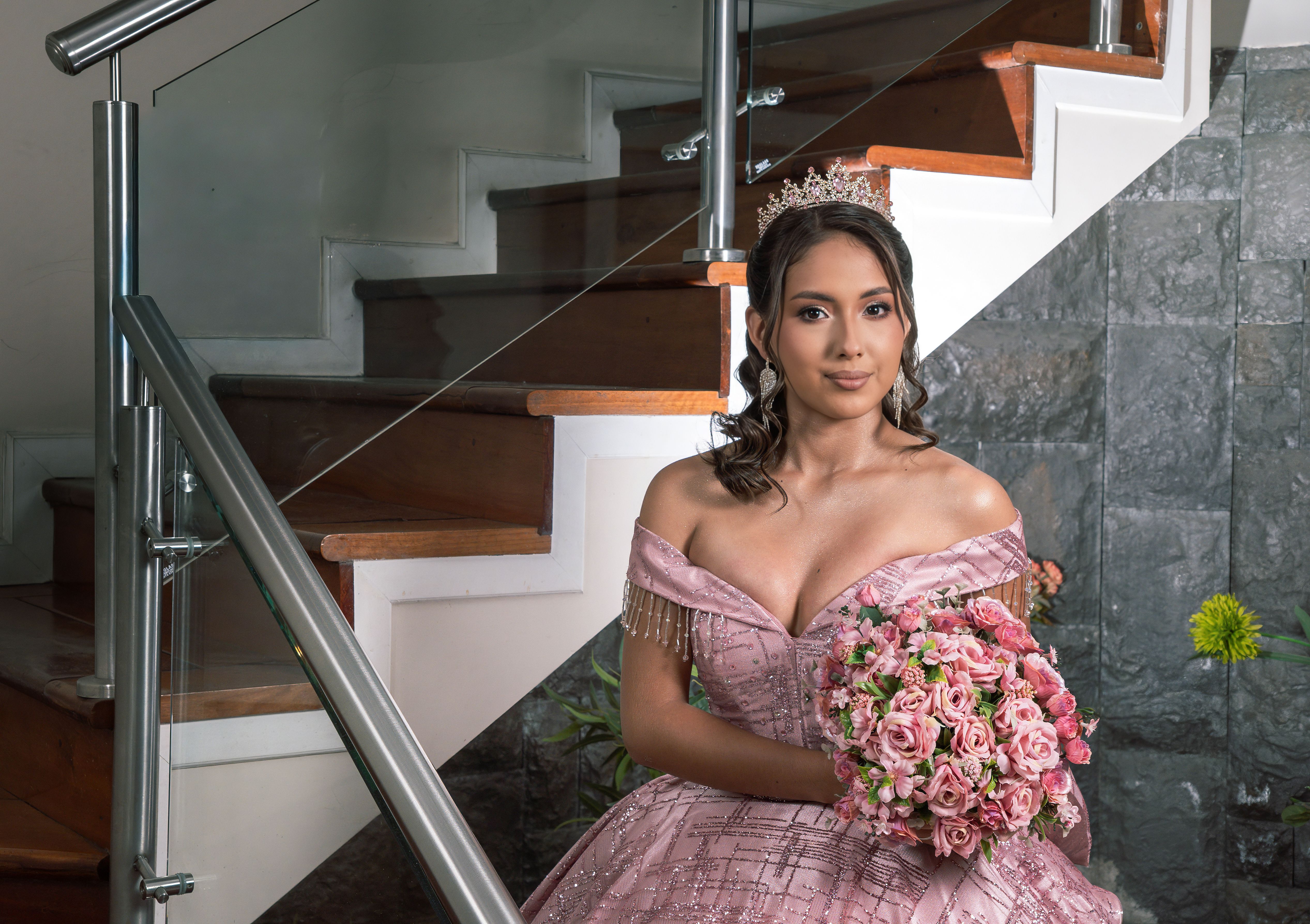 Elegant quinceañera in pink dress holding bouquet indoors, Santo Domingo de los Tsáchilas.