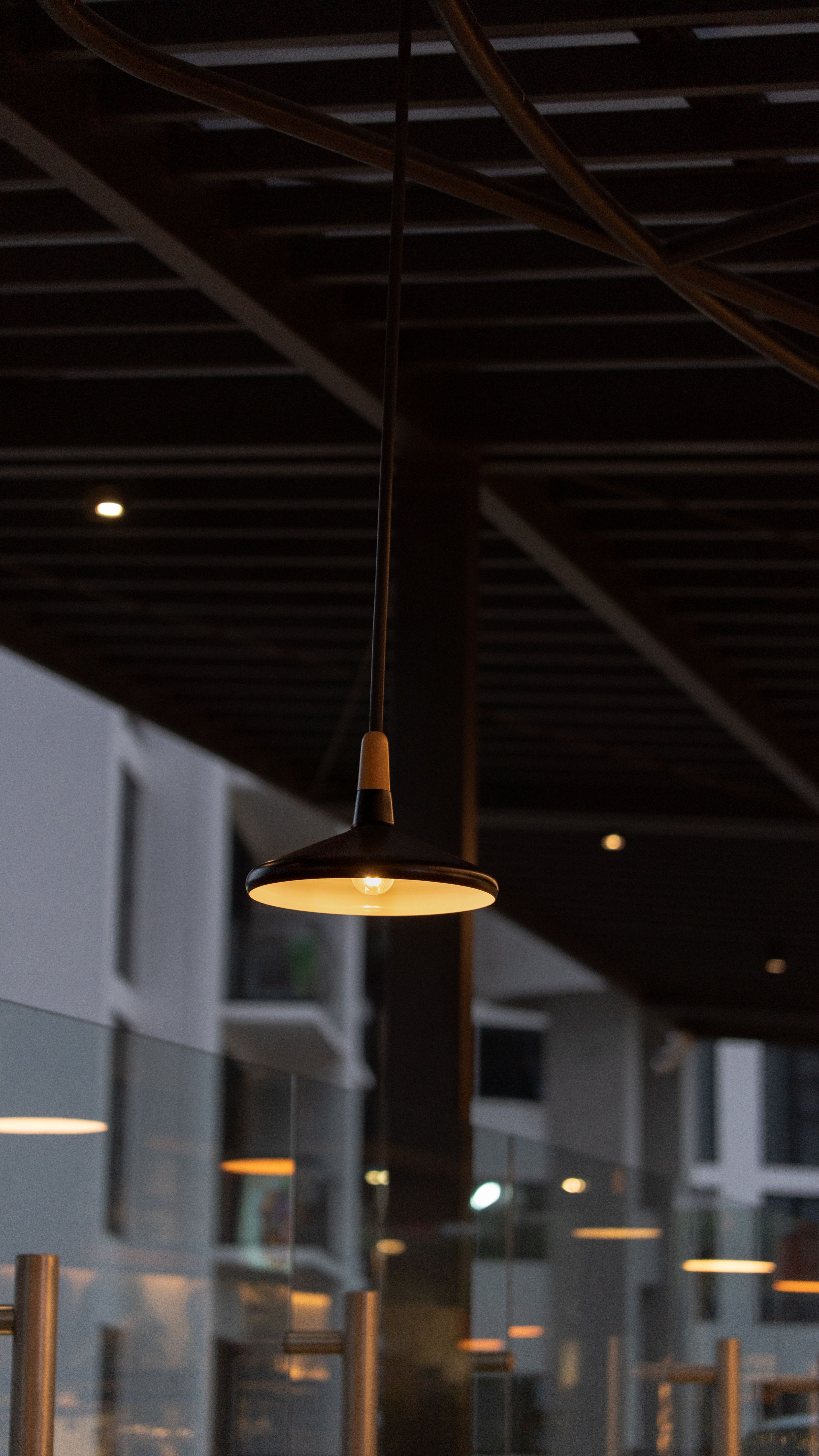 A stylish pendant light hanging in a modern outdoor setting at night, creating a warm ambiance.