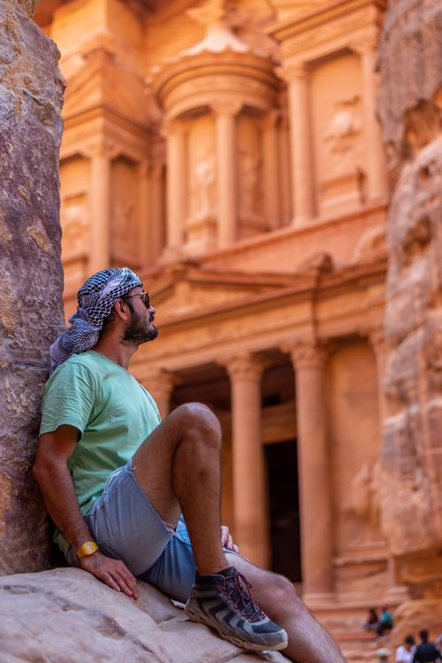 Free Tourist in traditional attire resting by the Al-Khazneh in Petra, Jordan. Stock Photo