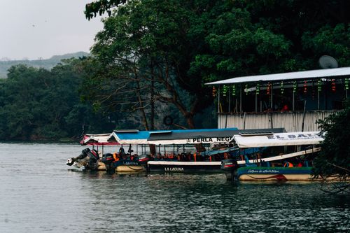 Free Peaceful riverside setting with boats docked by a colorful, decorated building. Stock Photo