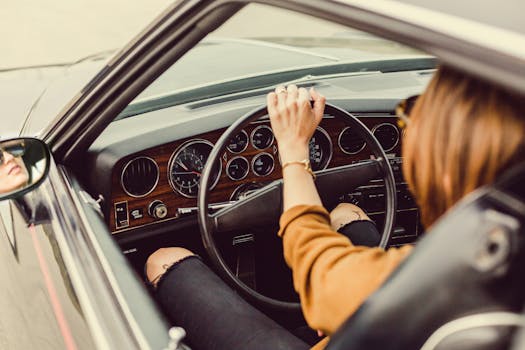 Woman driving a classic car with luxury interior, showcasing style and elegance.