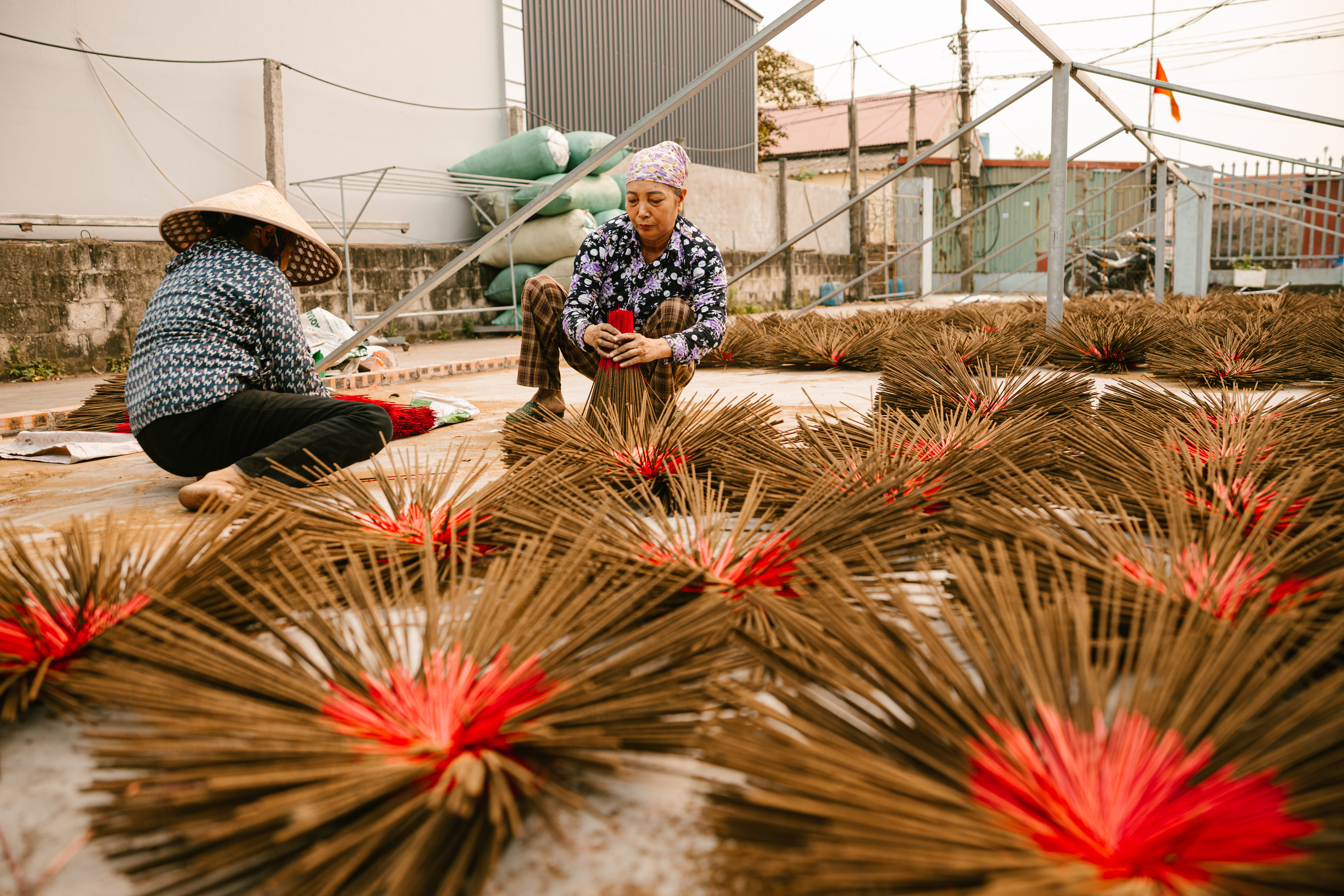 Artisans crafting incense sticks outdoors at a Vietnamese workshop.