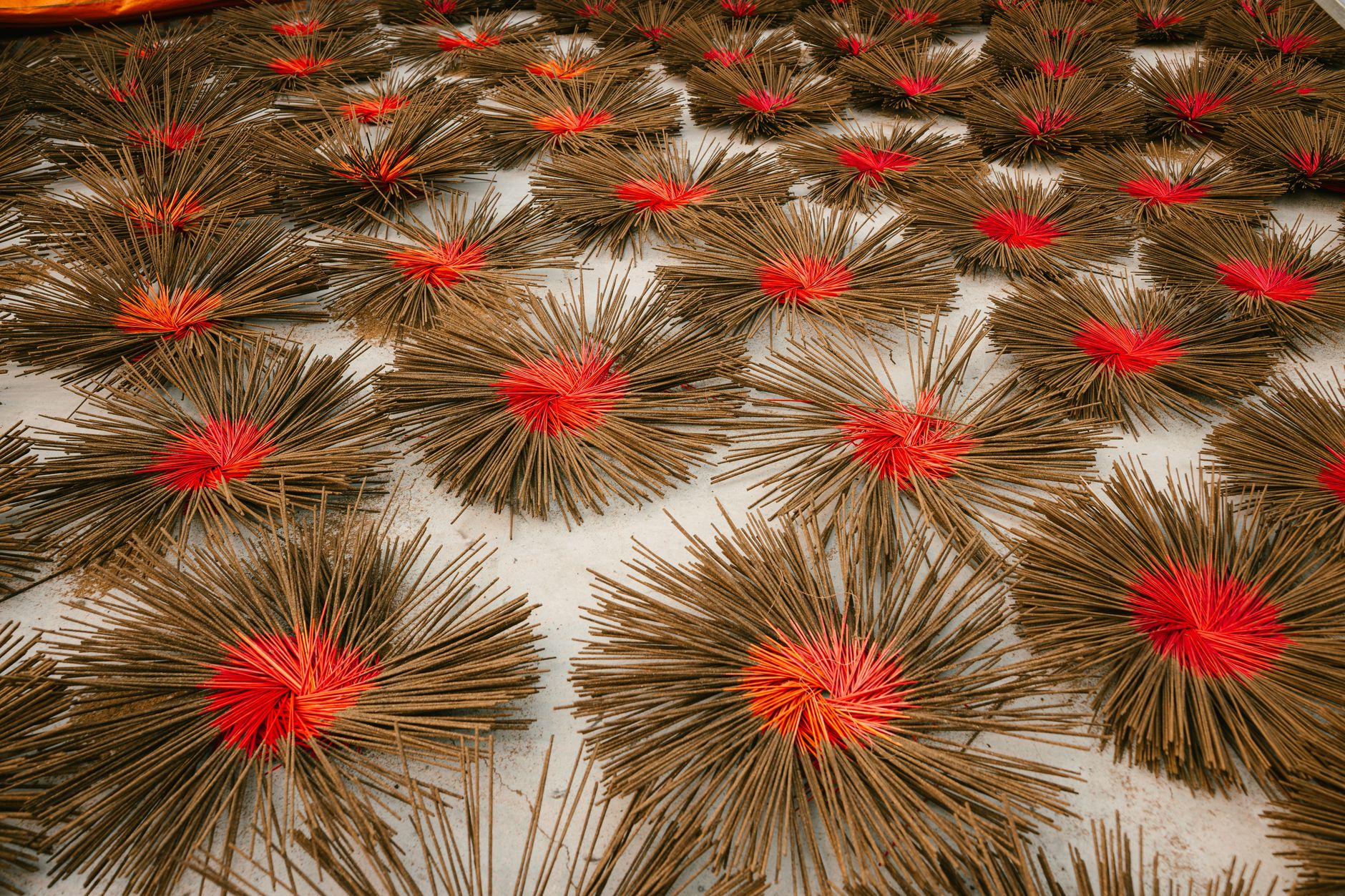 Une photo détaillée de bâtons d'encens avec des centres rouges séchant au soleil, mettant en valeur l'artisanat traditionnel.