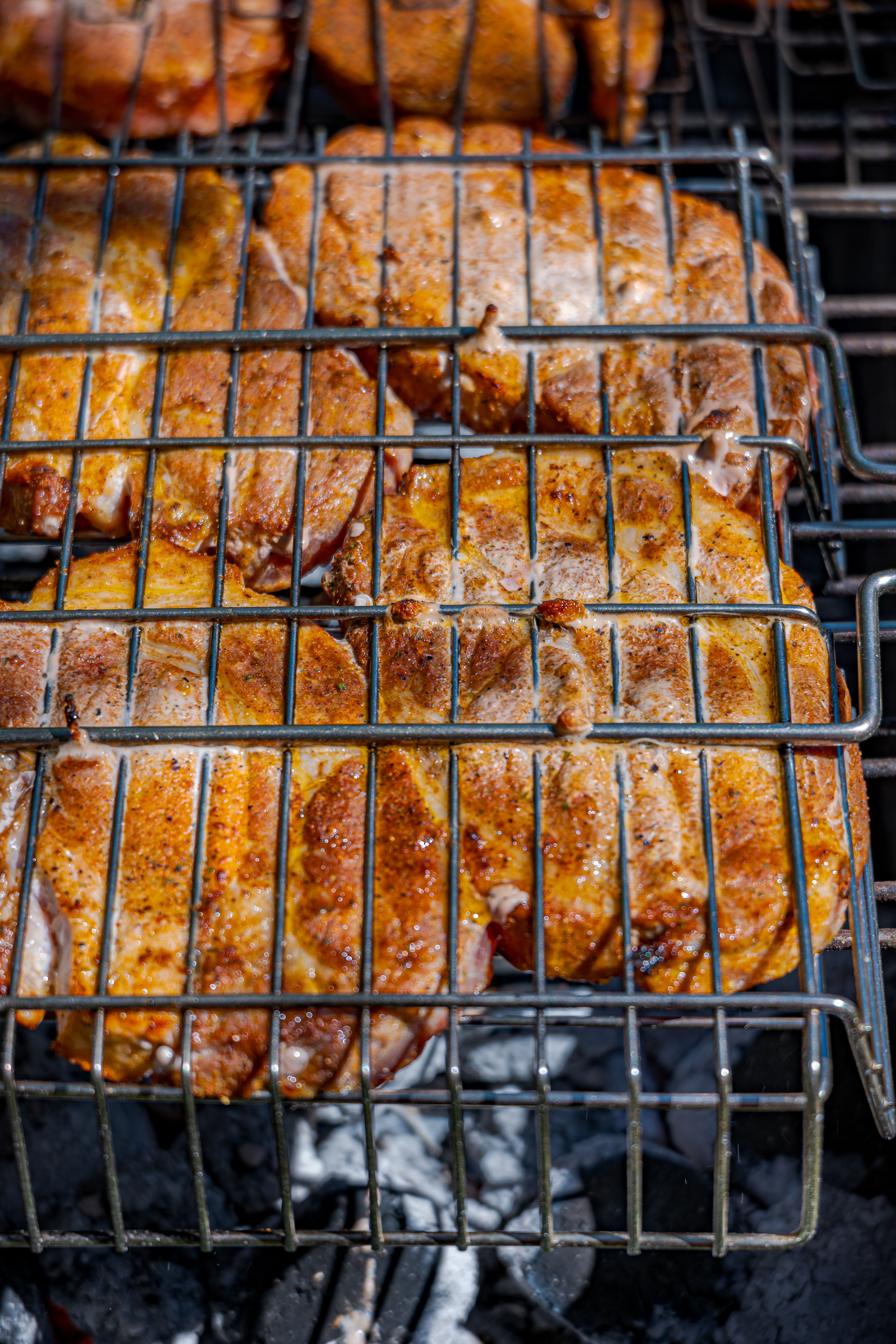Close-up of seasoned pork chops being grilled on an outdoor barbecue.