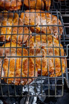 Close-up of seasoned pork chops being grilled on an outdoor barbecue.