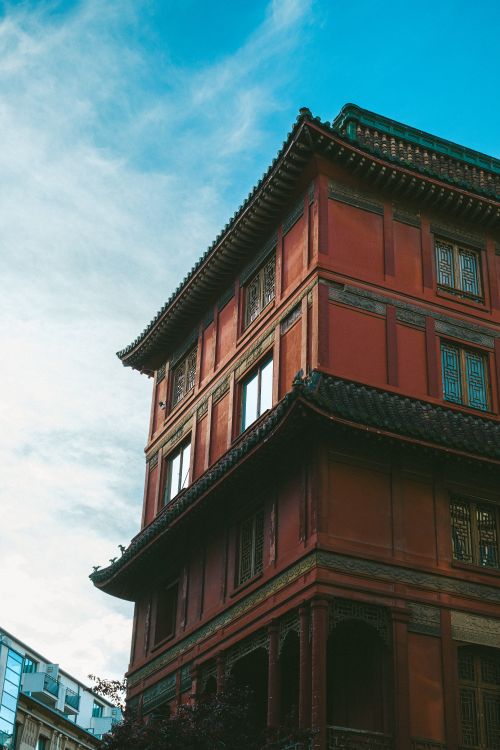 Free Traditional Asian building with ornate roof against a bright blue sky, showcasing intricate design. Stock Photo