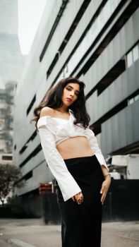 Stylish woman in a cityscape poses confidently against modern architecture. Chic and edgy fashion.
