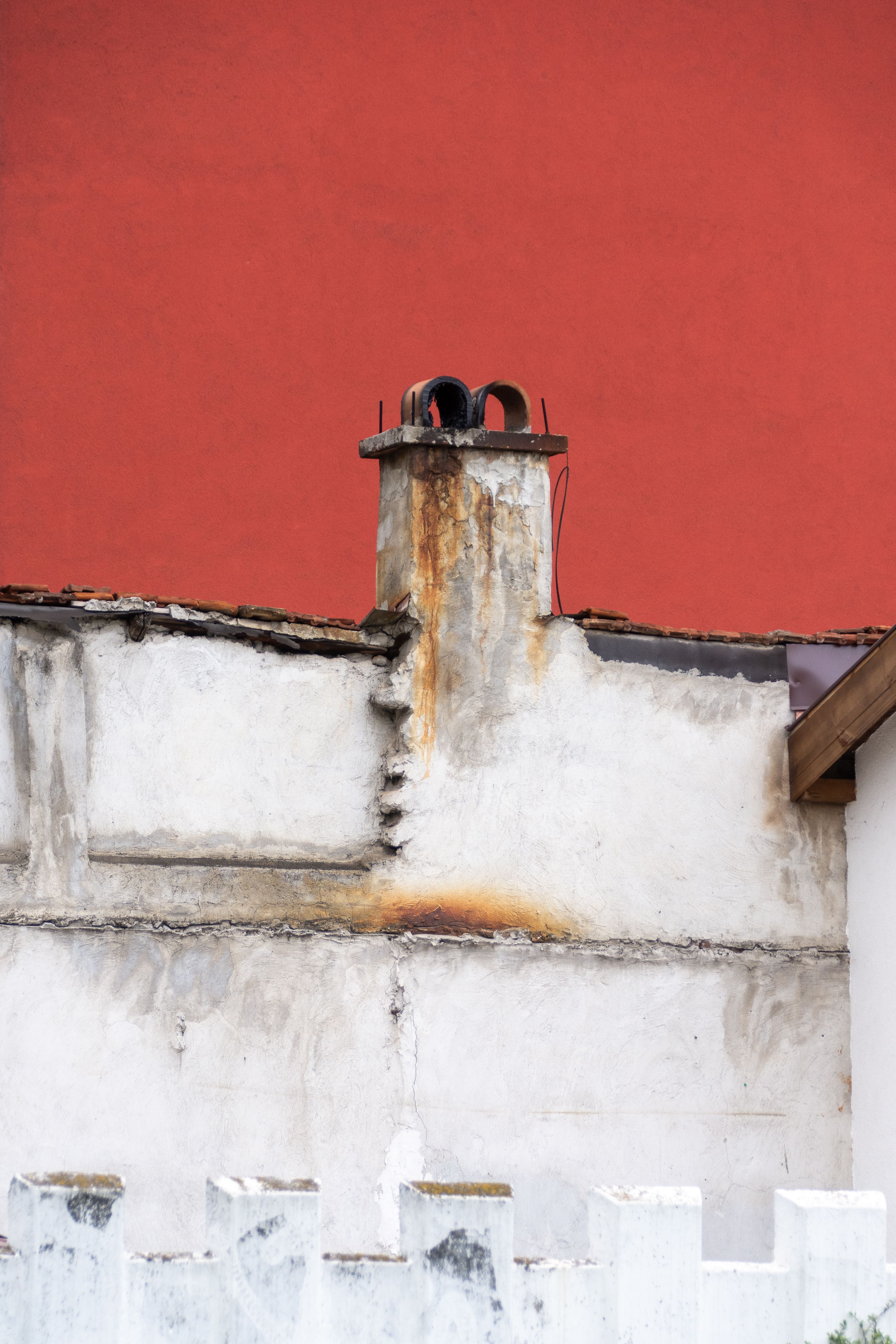 Aged Chimney Against Vibrant Red Wall · Free Stock Photo