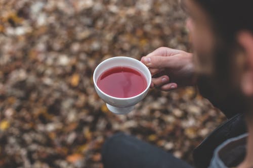 Person Holds White Ceramic Cup With Red Liquid