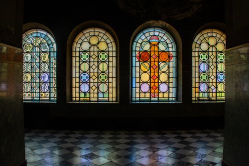 Free Vibrant stained glass windows with religious motifs illuminated from within a dim church setting. Stock Photo
