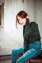 Charming Asian woman in denim and sweatshirt tucking hair behind ear looking gently at camera