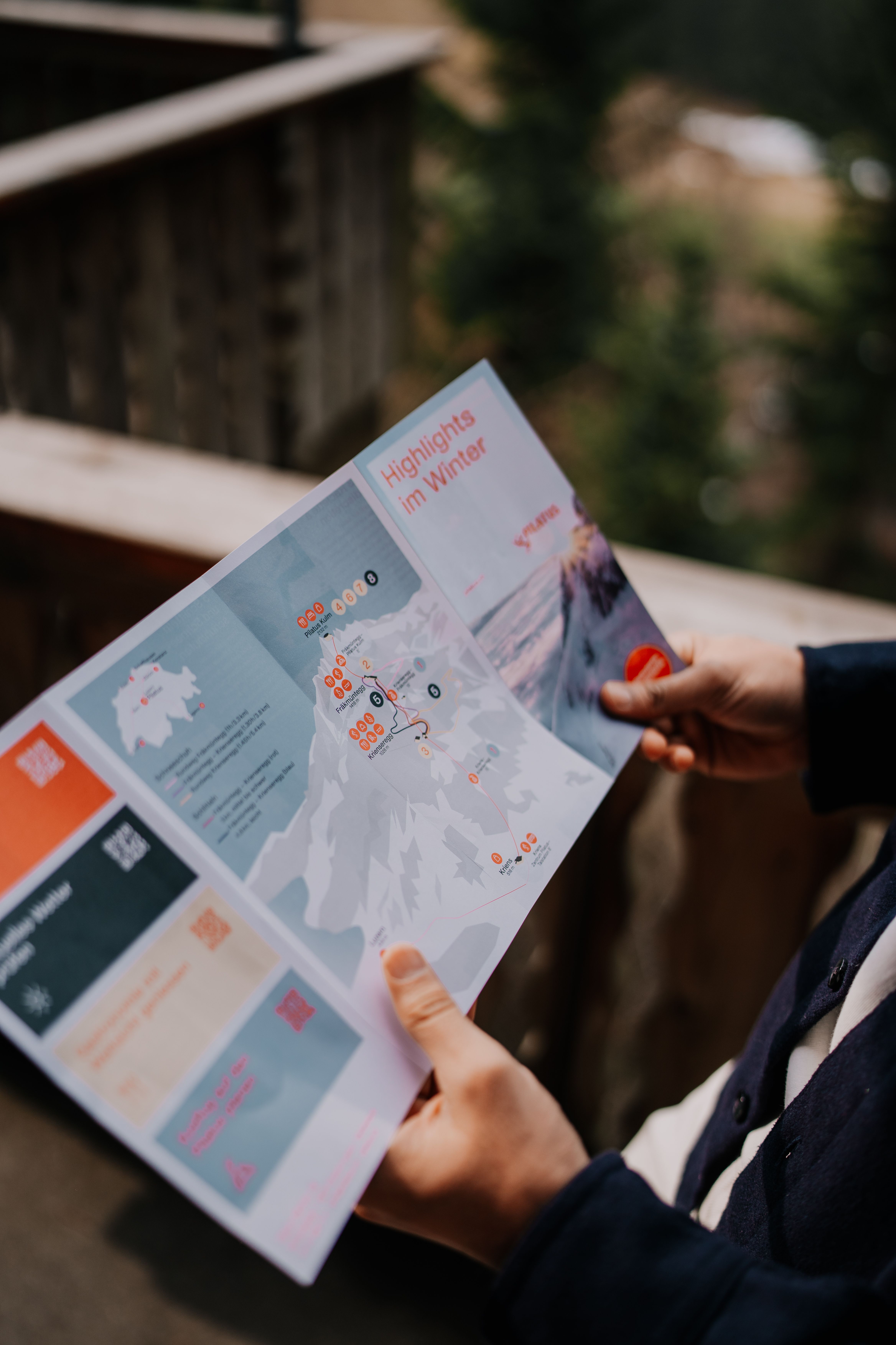 A person holds a winter highlights map outdoors in Alpnach, Switzerland.