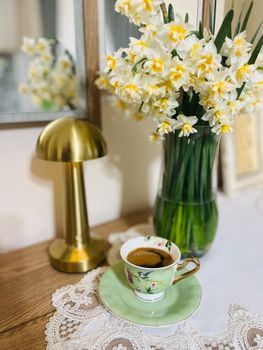 Charming indoor scene featuring a coffee cup beside blooming daffodils in a vase, perfect for lifestyle inspiration.