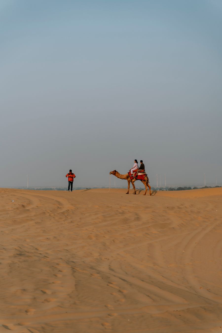 Couple riding a camel together across golden desert dunes at sunset