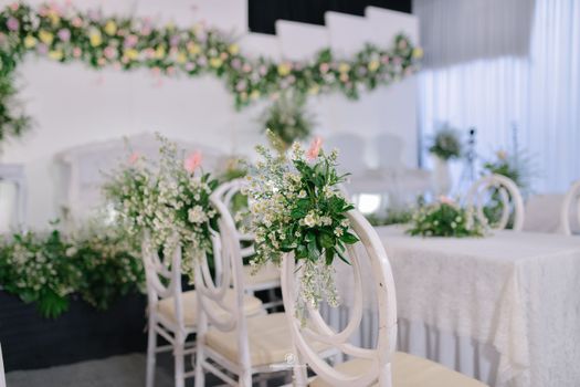 Elegant wedding venue featuring white chairs and lush floral arrangements, perfect for memorable events. - Fotografer Sidoarjo