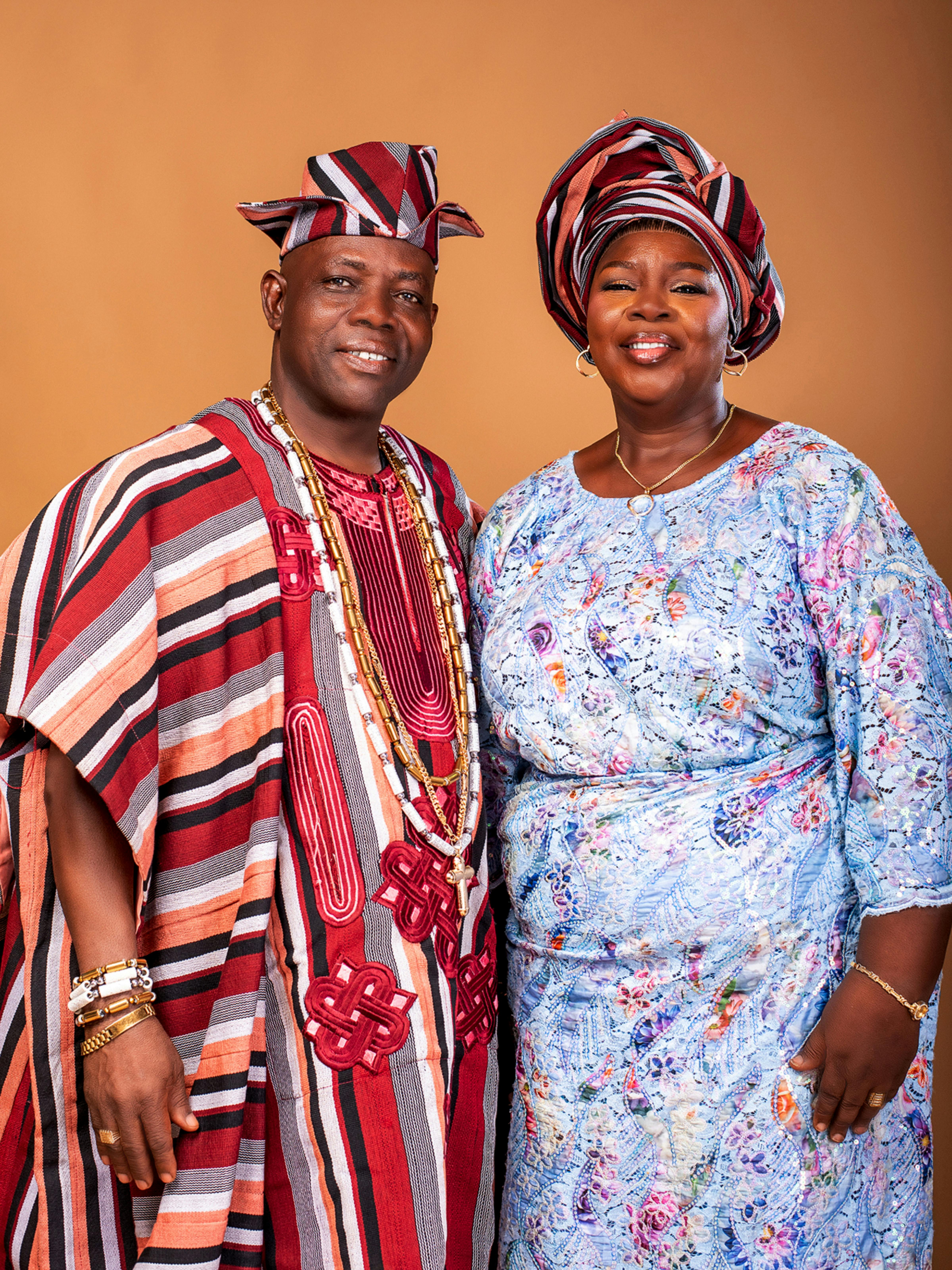 Smiling Nigerian couple elegantly dressed in traditional attire, capturing cultural beauty.